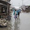 Una mujer camina por Les Cayes, en el sur de Haití, llevando consigo sus pertenencias mientras el agua de la inundación la rodea.