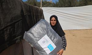 A woman in Gaza carries blankets distributed by UNICEF.
