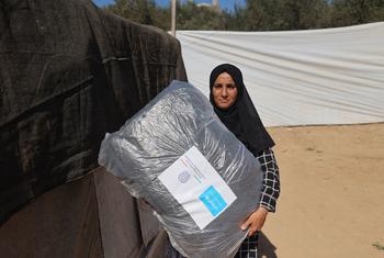 A woman in Gaza carries blankets distributed by UNICEF.