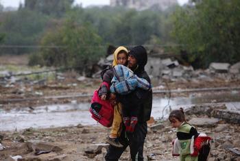 Un homme emmène ses enfants sur un terrain bombardé dans la bande de Gaza pendant la pause humanitaire temporaire.