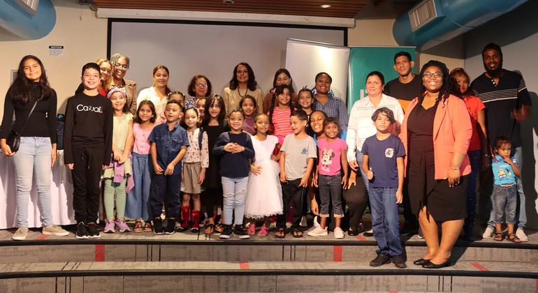 Venezuelan  students join their parents for a photo after receiving backpacks and stationery from the UN refugee agency.