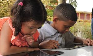 Two Venezuelan children use tablets at school.