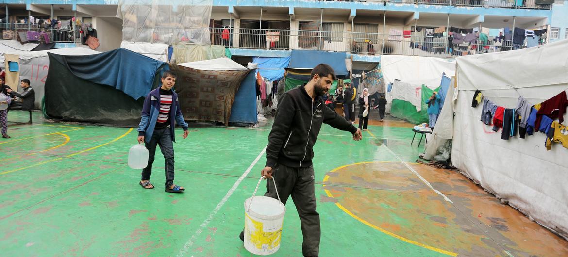 A man and boy collect water at a shelter for people displaced by the conflict in Gaza. (file)