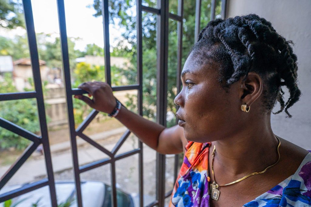 Mireille regarde à travers les barreaux de protection du centre GARR, pensant à son voyage de retour en Haïti.