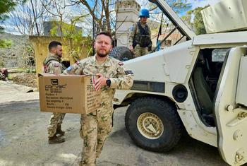 Irish and Polish UNIFIL peacekeepers in camouflage uniforms deliver aid boxes in Haddathah, south Lebanon.