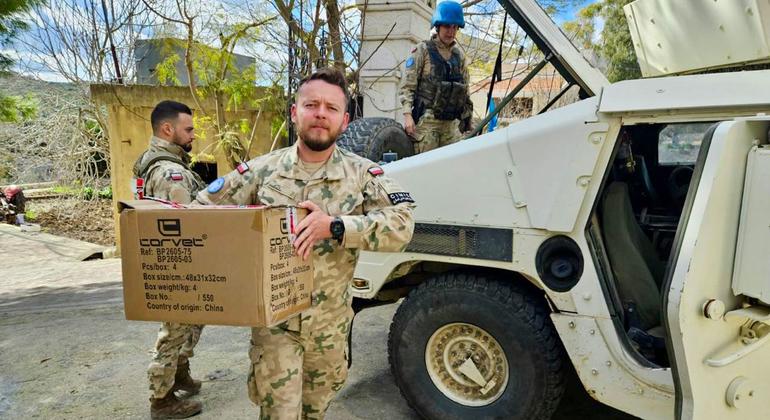 Irish and Polish UNIFIL peacekeepers in camouflage uniforms deliver aid boxes in Haddathah, south Lebanon.