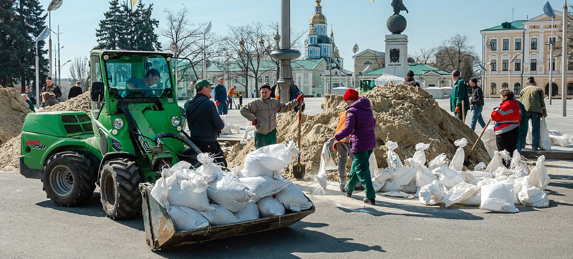 На фото: харьковчане обкладывают памятники мешками с песком. 