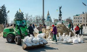 На фото: харьковчане обкладывают памятники мешками с песком. 