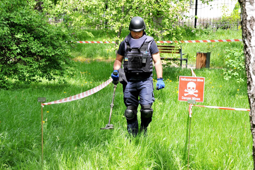 Seorang penjinak ranjau untuk Layanan Darurat Negara Ukraina menyapu tanah untuk mencari persenjataan dan ranjau darat yang belum meledak.