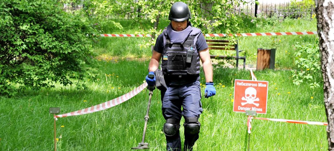 Un desminador del Servicio Estatal de Emergencias de Ucrania barre el terreno en busca de artefactos explosivos sin detonar y minas terrestres.
