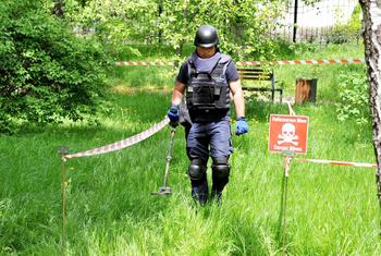 Um desminador do Serviço Estatal de Emergência da Ucrânia varre o terreno em busca de munições não detonadas e minas terrestres