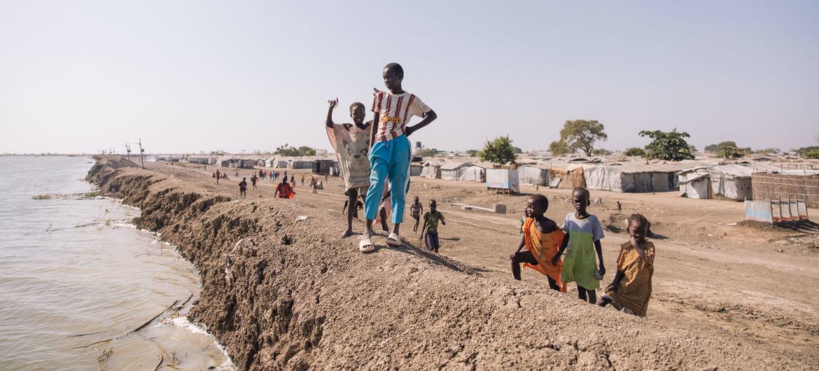 在南苏丹的一座流离失所者营地里，孩子们站在堤坝边。
