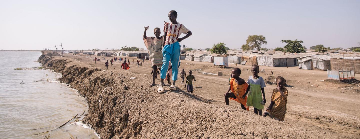 Des enfants se tiennent près d'une digue dans un camp pour personnes déplacées par le conflit au Soudan du Sud.