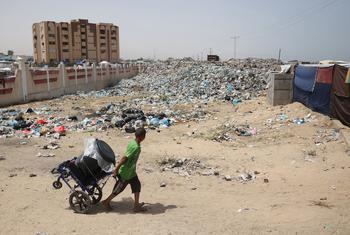 A child pulls a cart while searching through waste piled up near the tents for Internal Displaced People (IDPs) in Rafah, southern the Gaza Strip...