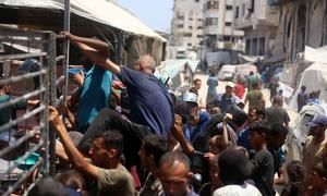 Hombres escalan las barreras de una cocina comunitaria en el oeste de la Ciudad de Gaza en busca de comida (foto de julio de 2025).