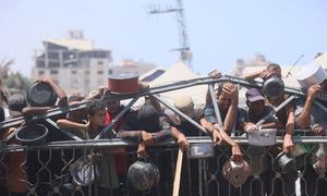 People wait for food at a community kitchen in western Gaza City.