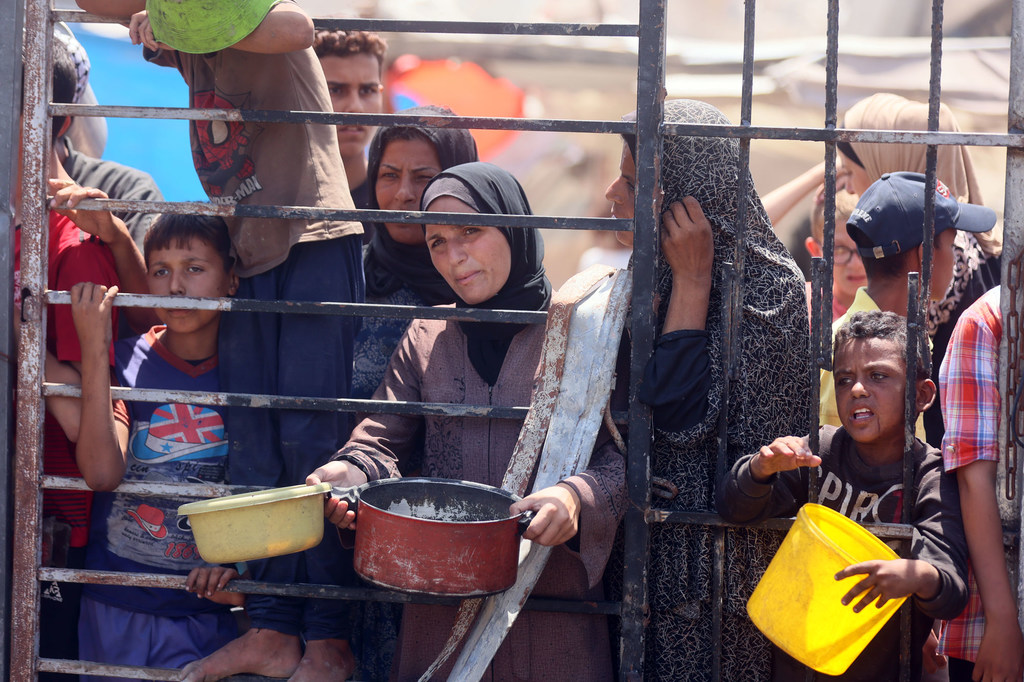 Des femmes et des enfants attendent de la nourriture dans une cuisine communautaire à l'ouest de la ville de Gaza.