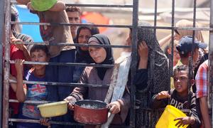 Women and children wait for food at a community kitchen in western Gaza City.
