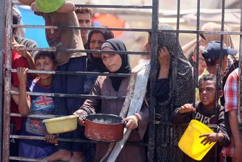Women and children wait for food at a community kitchen in western Gaza City.
