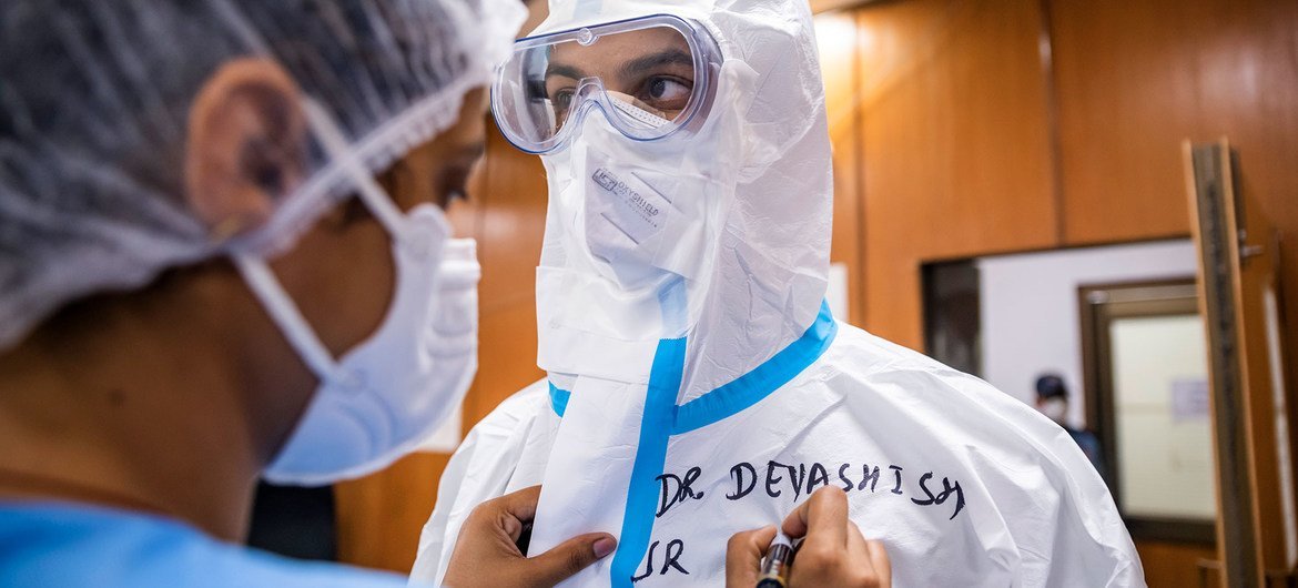 भारत की राजधानी नई दिल्ली के एक अस्पताल में एक नर्स, डॉक्टर को कोविड वॉर्ड में जाने से पहले तैयार कर रही है. 