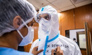 Una enfermera prepara a un médico para entrar en el ala de COVID de un hospital en Nueva Delhi, India.