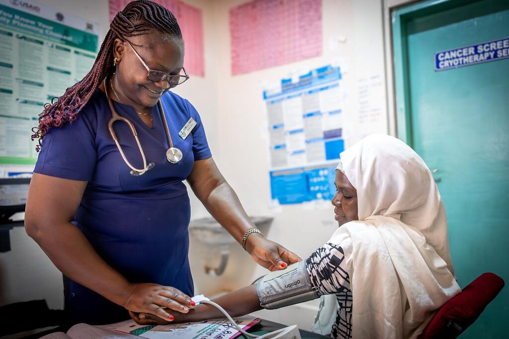 Un professionnel de la santé au Kenya effectue un contrôle de la pression artérielle d'un patient lors d'un dépistage du cancer.