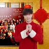 一个穿着传统红色中国服装的男子站在2026年联合国春节嘉年华的群组照片前, 周围有红灯和中国等节日装饰.