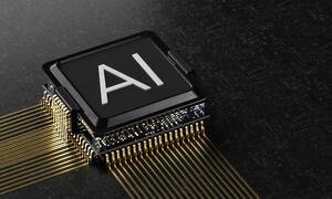 A close-up of a computer chip with 'AI' printed on its surface, connected by gold pins on a dark circuit board.