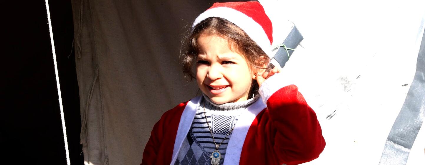Une jeune fille palestinienne en costume de Père Noël, debout parmi les tentes des familles déplacées dans le nord de la ville de Gaza.