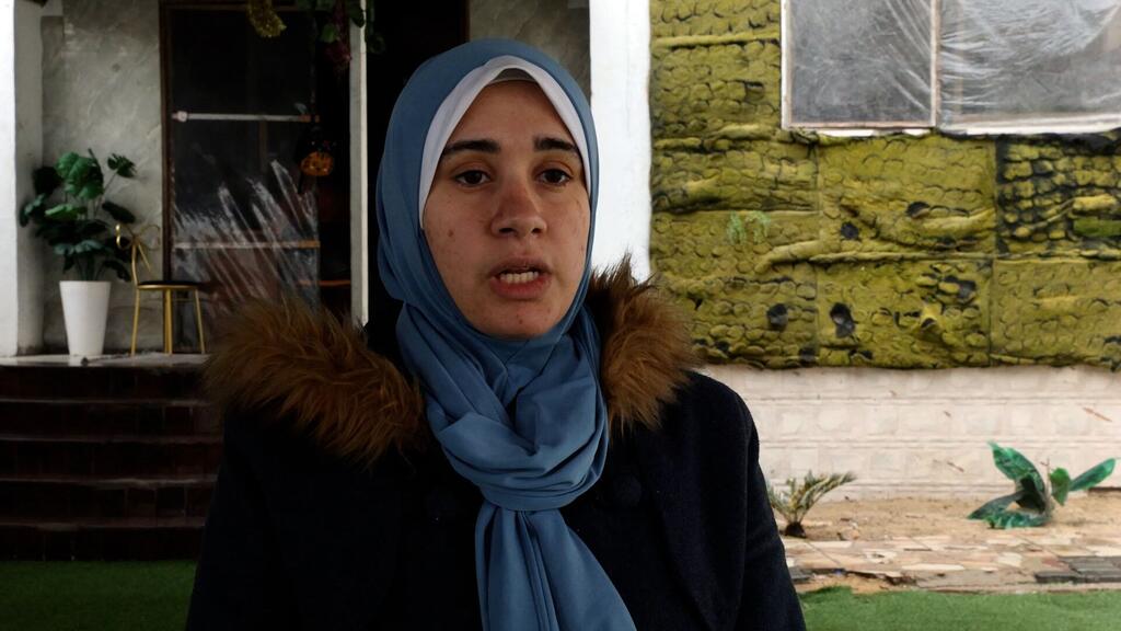 Un retrato de una mujer palestina con un hijab azul y un abrigo oscuro con un collar de piel, hablando durante una entrevista para el Día de Concientización sobre el Autismo en Gaza.