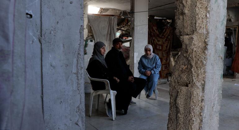 عائلة فلسطينية تجلس داخل مبنى مدمر في غزة، محاطة بالانقاض والدمار.