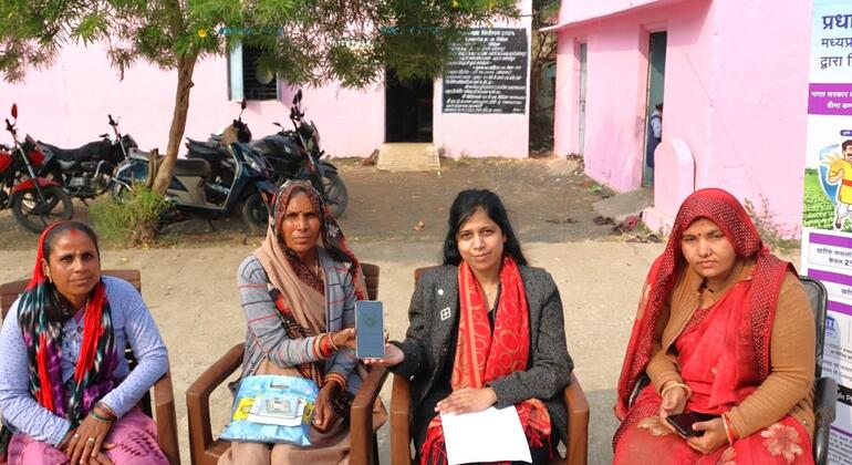 लक्ष्मी राठिया, फ़ील्ड टीम से फ़सल बीमा ऐप का उपयोग करना और अपने दावे की स्थिति से जुड़ी जानकारी प्राप्त करना सीख रही हैं.