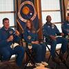 Cuatro astronautas de la misión Artemis II de la NASA, con trajes de vuelo azules, se sientan en el escenario durante una conferencia de prensa con las banderas de la NASA y de Estados Unidos detrás de ellos.