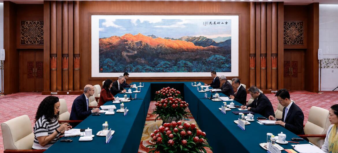 一群专业人士围坐在大型会议桌旁，背景是一间正式的会议室，墙上挂着一幅大型中国山水画。