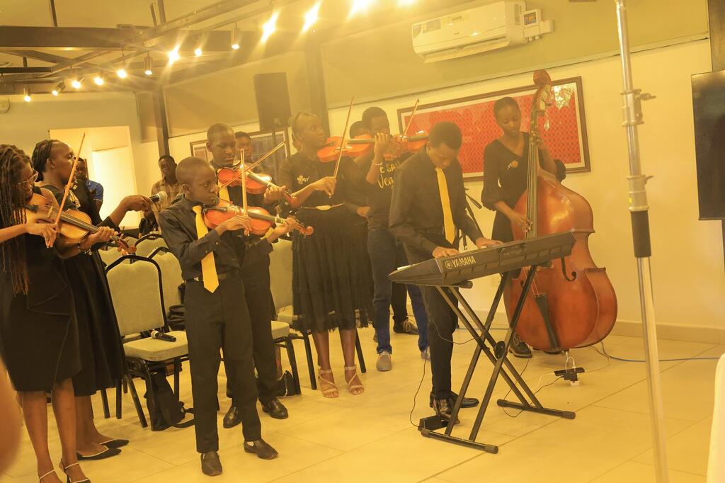Kikundi cha wanamuziki wachanga wanacheza kwa kutumia violini, cello, na kibodi kwenye jukwaa la ndani.