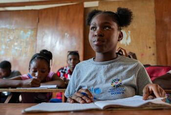 Dieussika, une enfant déplacée d'Haïti, s'assoit dans sa salle de classe pour prendre des notes et travailler.
