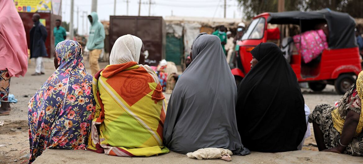 أربع نساء يرتدين الحجاب يجلسن على جانب طريق ترابي في السودان.