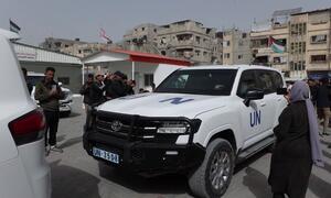A UN vehicle prepares to transport patients from Al-Amal Hospital in Rafah, Gaza, affiliated with the Palestinian Red Crescent Society, as people gather around.