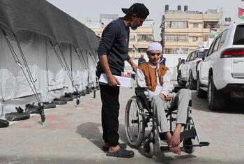 Un patient en fauteuil roulant est aidé par un membre du personnel de l'hôpital Al-Amal à Gaza, affilié à la Société du Croissant-Rouge palestinien, pour se préparer au transport.