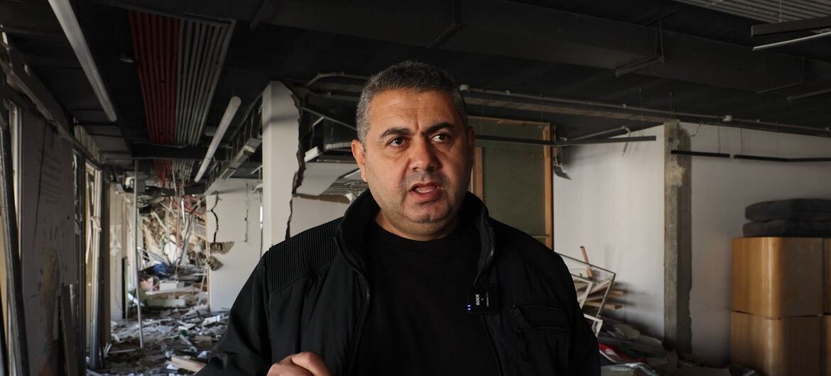 Um homem está em um edifício destruído em Gaza, cercado por escombros e detritos, falando com a câmera.