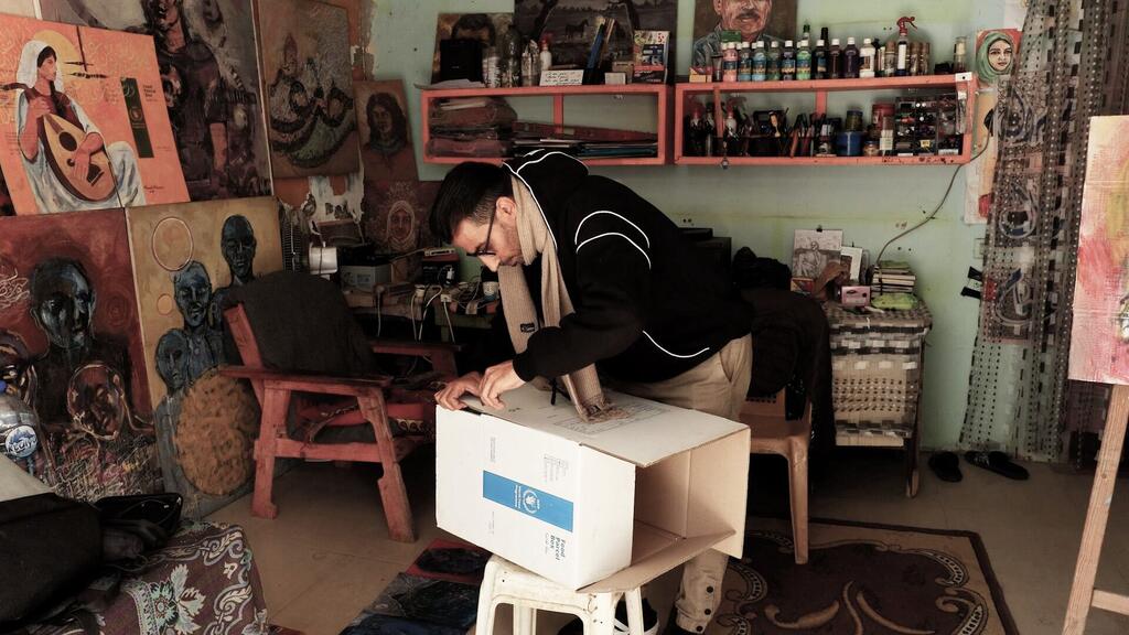 الفنان الفلسطيني أحمد مهنا يستخدم صناديق المساعدات المقدمة من برنامج الأغذية العالمي لرسم لوحاته عليها.