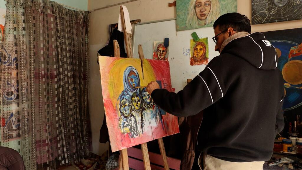 الفنان الفلسطيني أحمد مهنا يعمل على إحدى لوحاته في مرسمه بمخيم البريج للاجئين في وسط قطاع غزة.
