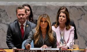 Melania Trump speaking at a United Nations meeting, seated at a desk with a 'President United States' placard.