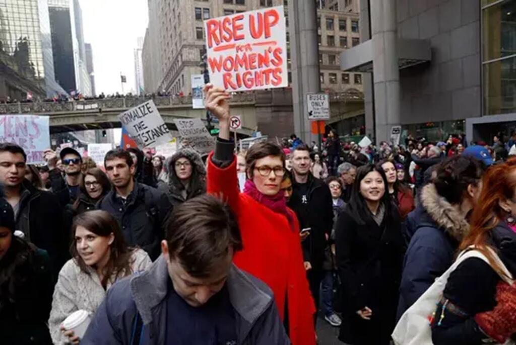 Une foule de manifestants défilent à New York lors de la Marche des femmes 2017, tenant des pancartes défendant les droits des femmes et l'égalité des sexes.