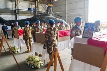 联合国安理会维和部队穿着蓝色和伪装制服的维和部队在一个机内举行葬礼期间, 在背景中搭载直升机的葬礼中, 站在覆盖棺材旁边.