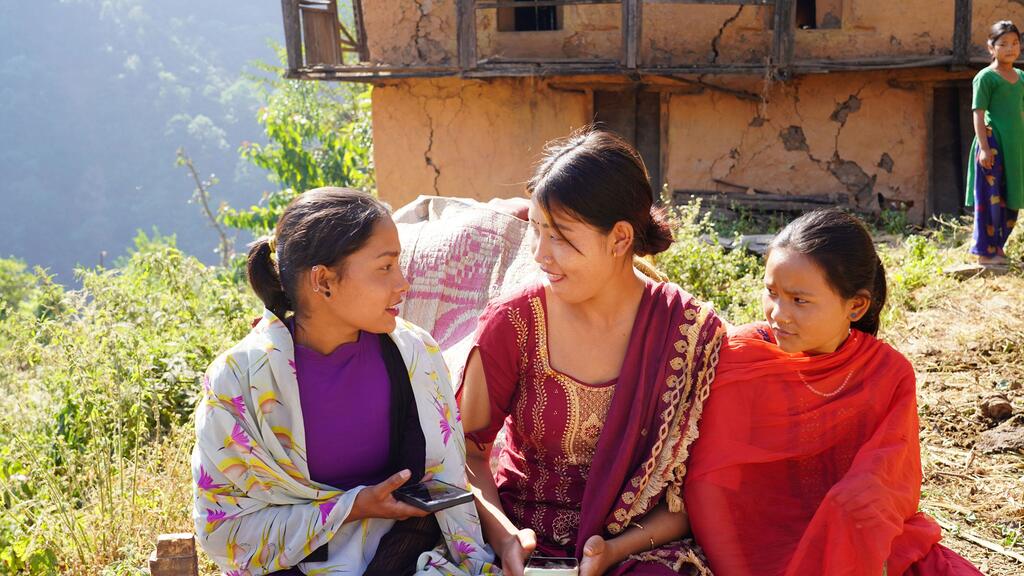 Wanawake watatu walishiriki katika mazungumzo huko Nagladh, wilaya ya Jajarkot, Nepal, kama sehemu ya majibu ya UNFPA kwa tetemeko la ardhi, wakisisitiza juhudi za kusaidia wanawake na wasichana katika eneo lililoathirika.