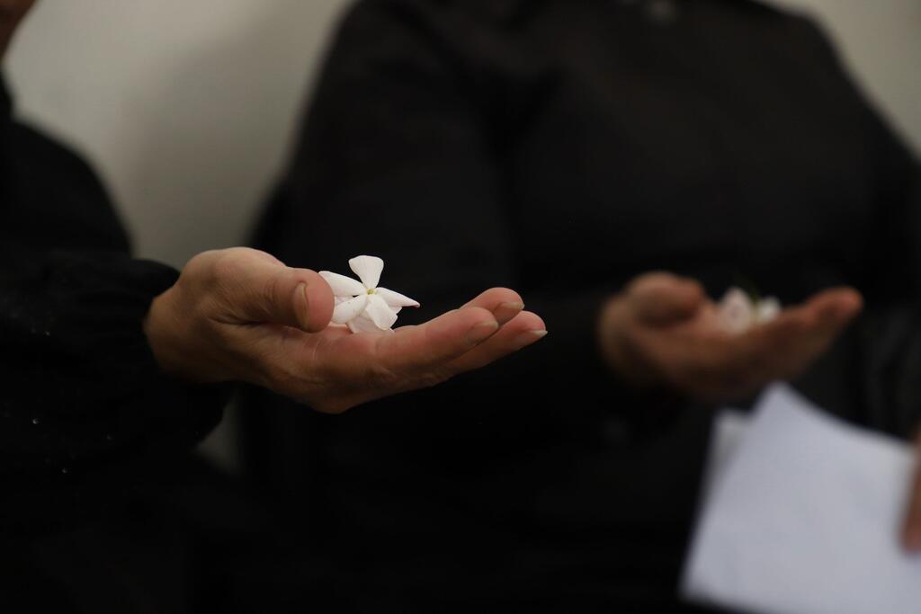 Dos mujeres sostienen delicadas flores blancas en sus palmas, que simbolizan la esperanza y la resiliencia durante una reunión de empoderamiento apoyada por el UNFPA en la zona rural de Siria.
