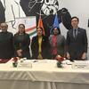 न्यूयॉर्क में एक हिंदी दिवस कार्यक्रम के दौरान पांच भारतीय राजनयिक एक सम्मेलन मेज पर खड़े हैं, पृष्ठभूमि में नाम प्लेट और राष्ट्रीय ध्वज हैं।