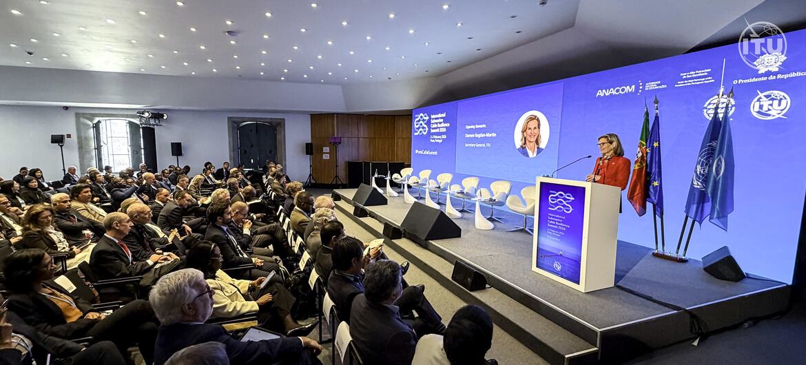 Un conférencier s'adresse à un public lors du Sommet des câbles sous-marins organisé par l'UIT au Portugal, avec des logos de l'UIT et de l'ANACOM affichés sur scène.