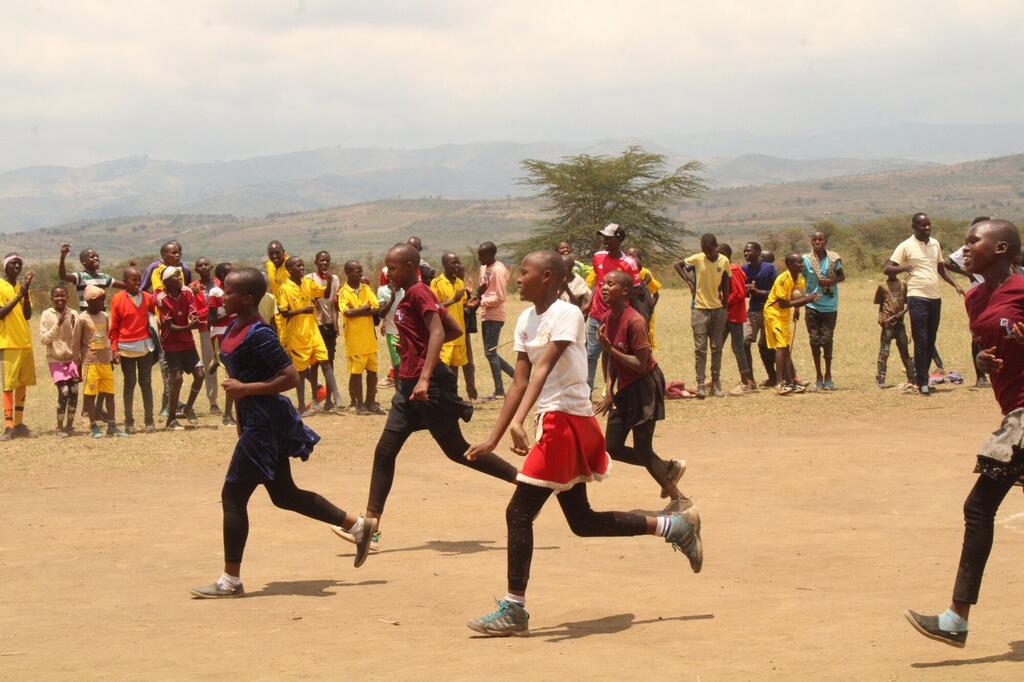 Watoto wanashiriki katika mbio za mbio wakati wa tukio la kampeni ya uhamasishaji wa UNFPA Kenya FGM huko Narok, kuonyesha ushiriki wa jamii na ushiriki wa vijana.
